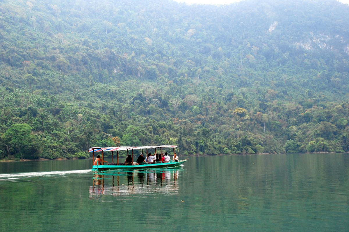 Tourist boat cruising on Ba Be Lake surrounded by limestone mountains